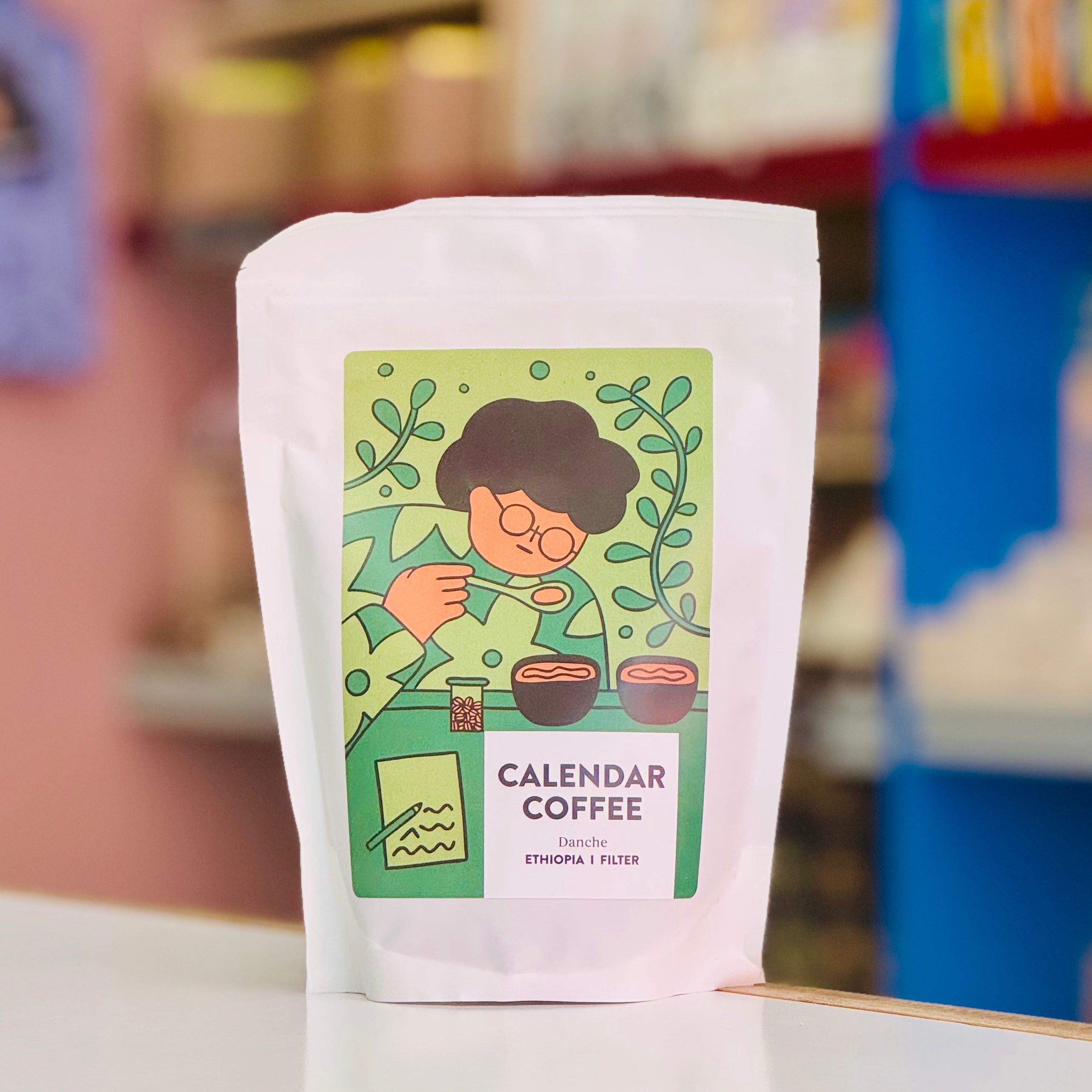 Coffee package with a colorful label featuring an illustration of a person and text on a blurred background.
