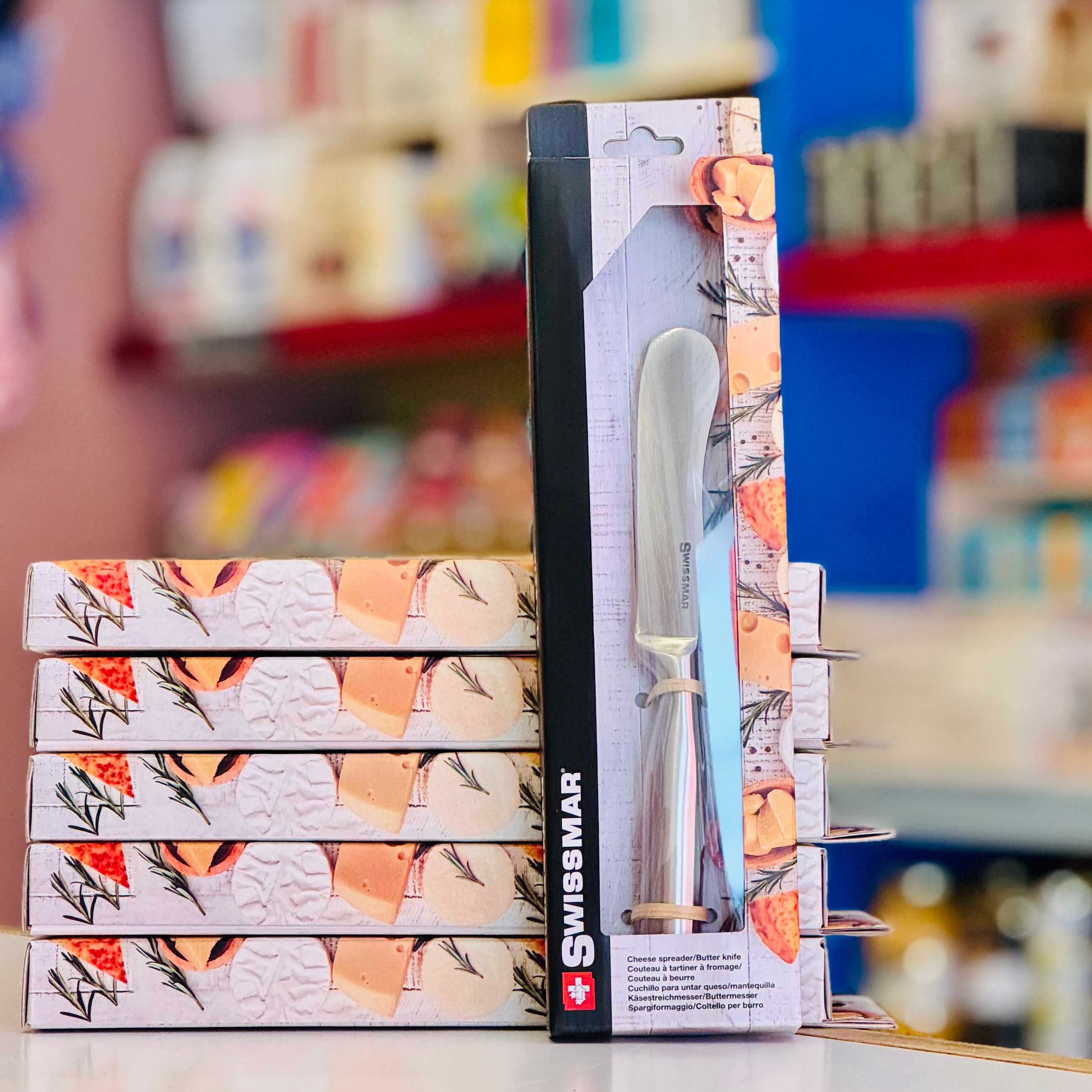 Packaged Swissmar knife with decorative design on a blurred store shelf background
