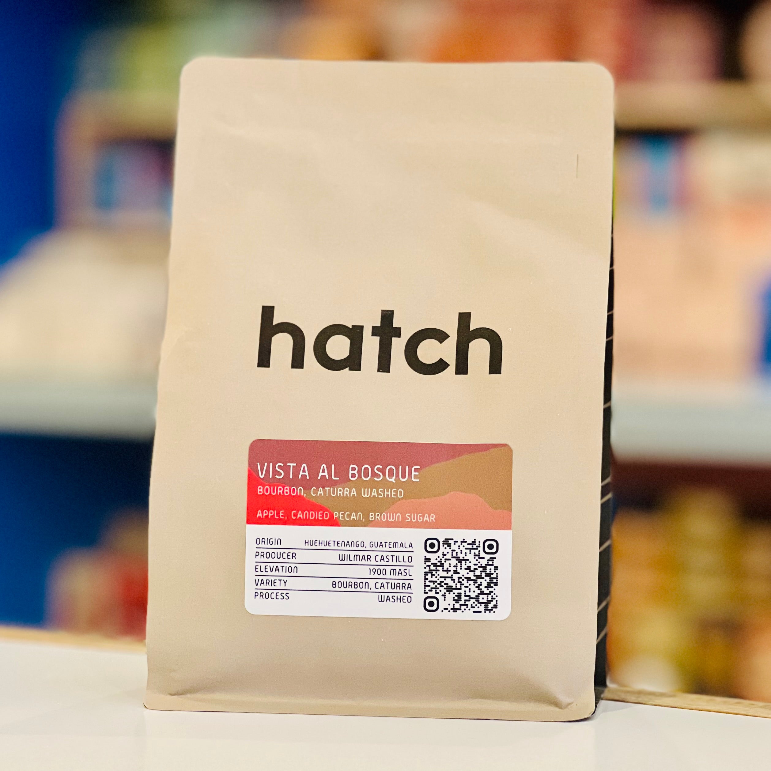 Coffee bag with 'hatch' branding on a blurred store shelf background