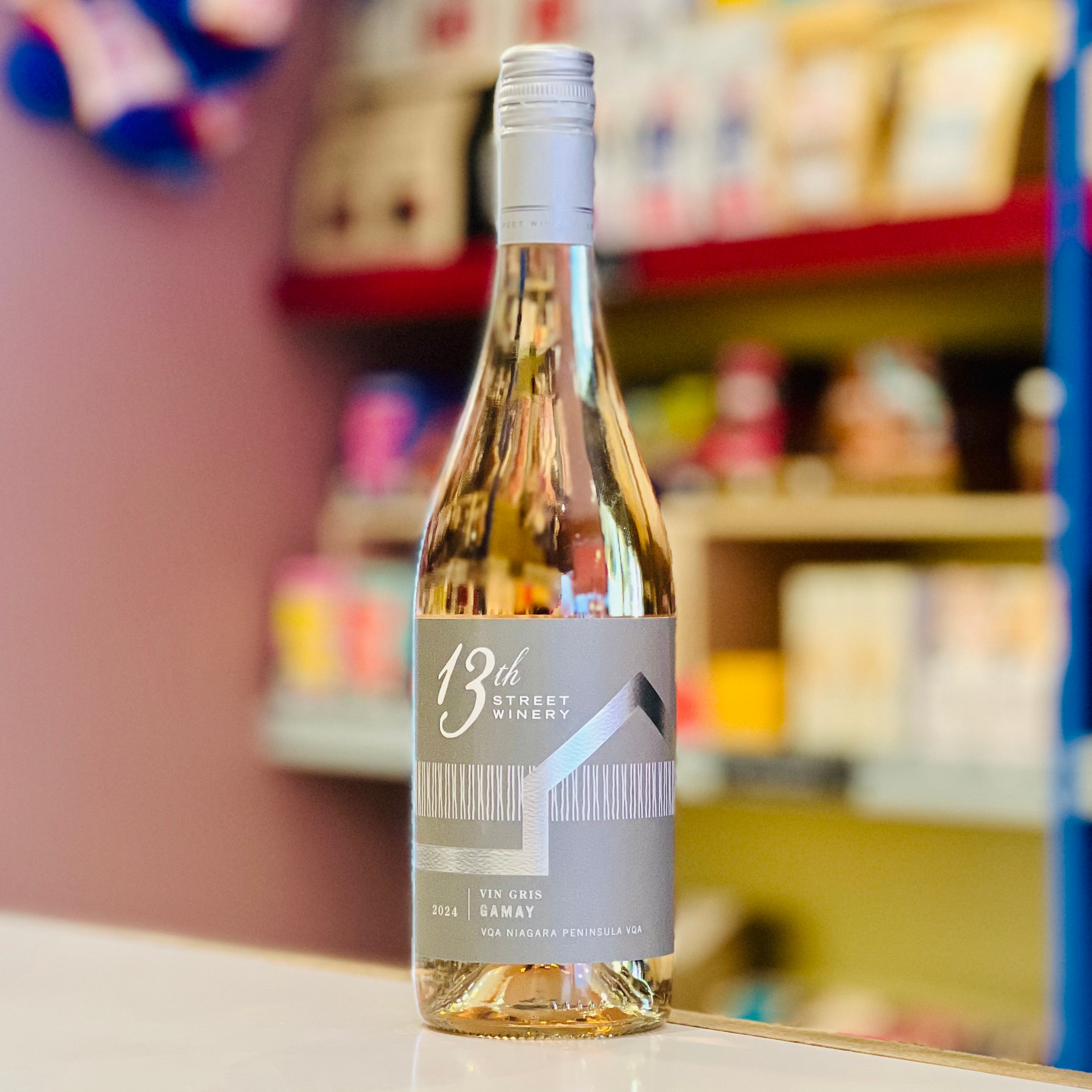 Bottle of 13th Street Winery wine on a counter with shelves in the background
