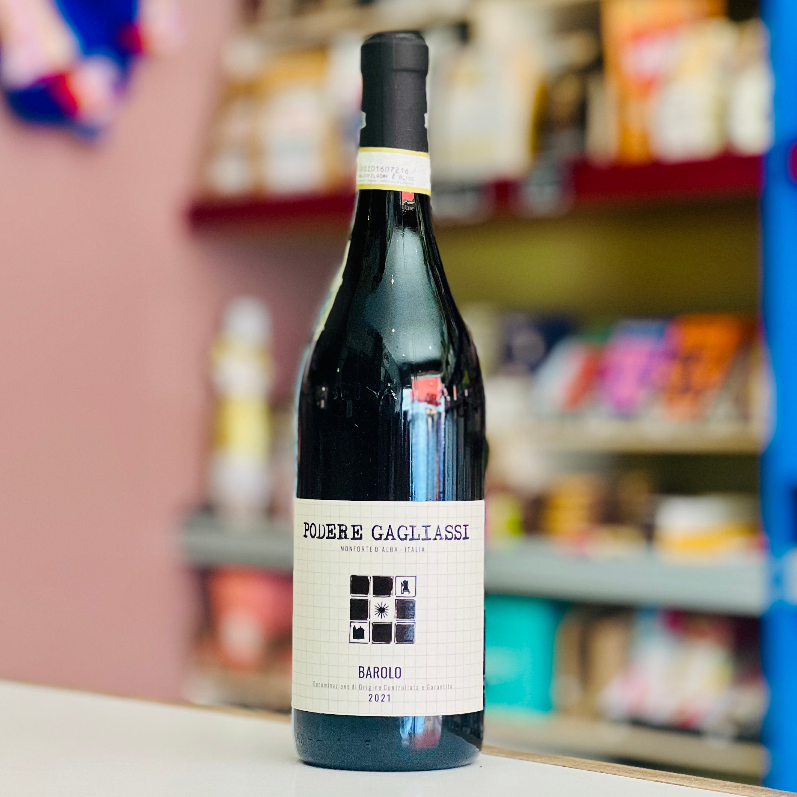 Bottle of Podere Gagliassi Barolo wine on a shelf with blurred store background