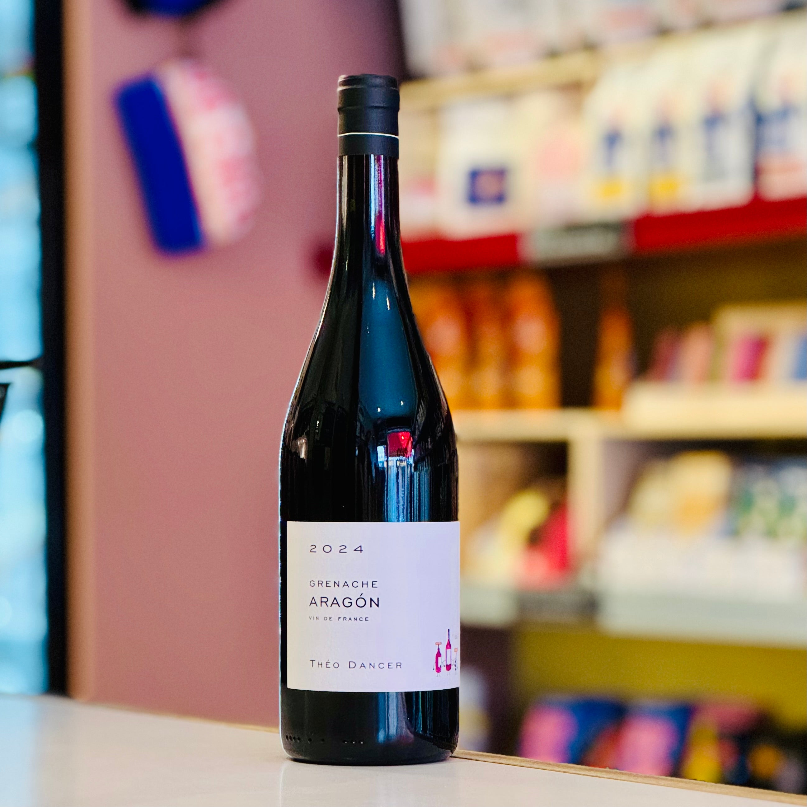 Wine bottle labeled '2024 Grenache Aragon' on a shelf with blurred store background