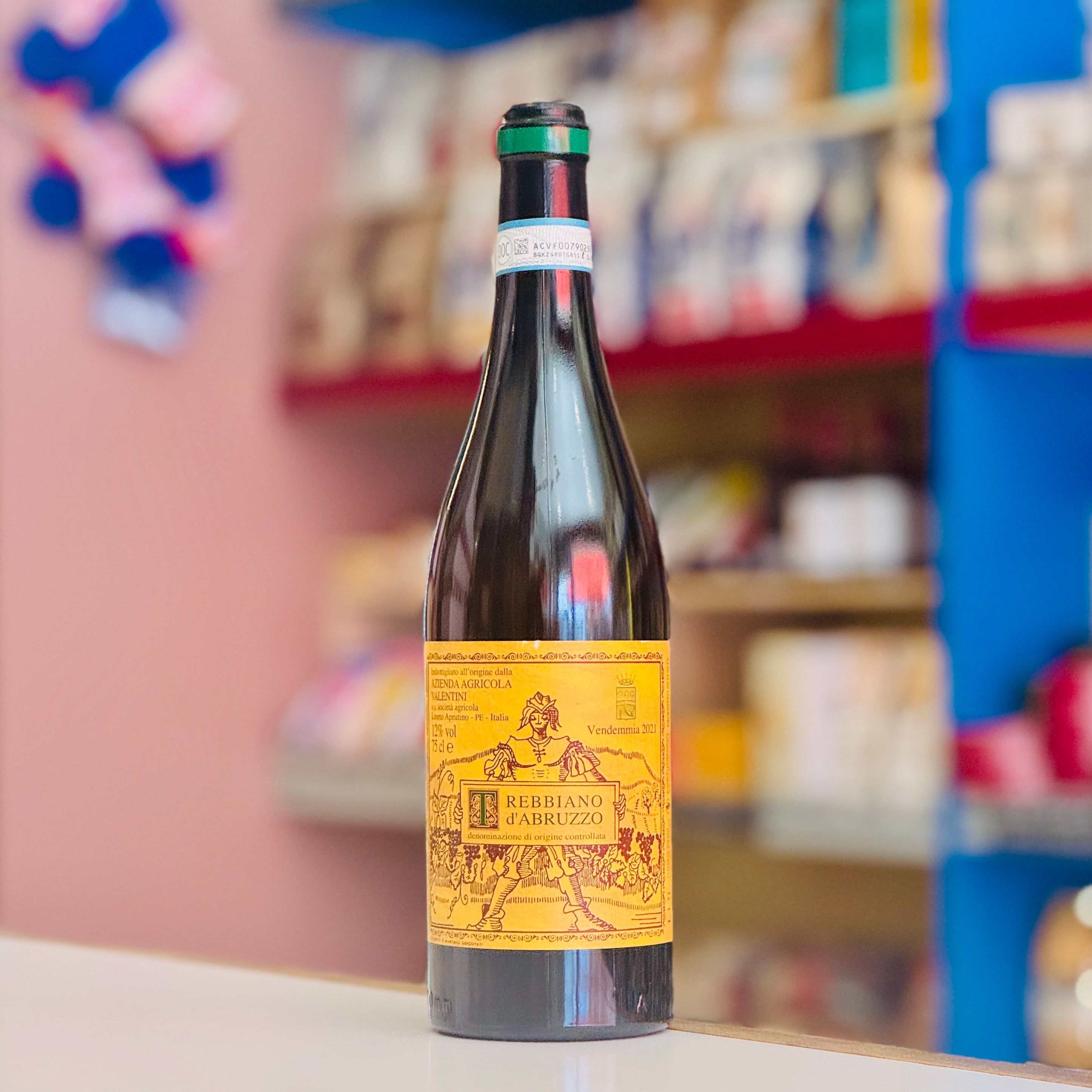 Wine bottle Valentini Trebbiano d'Abruzzo sitting on a table with a blurred background.