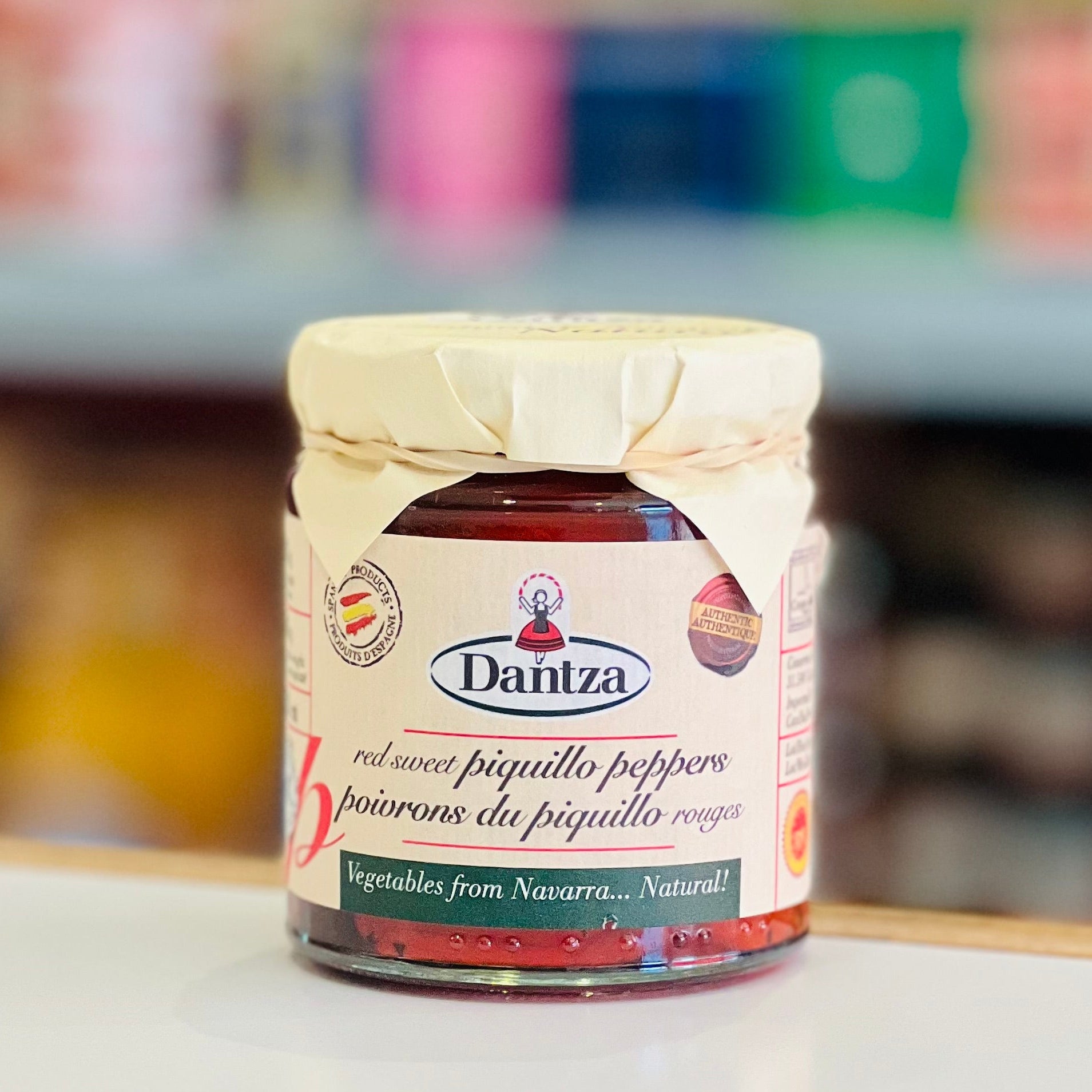 Jar of Dantzá brand piquillo peppers on a shelf with blurred background